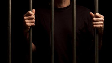 man in black shirt behind prison bars