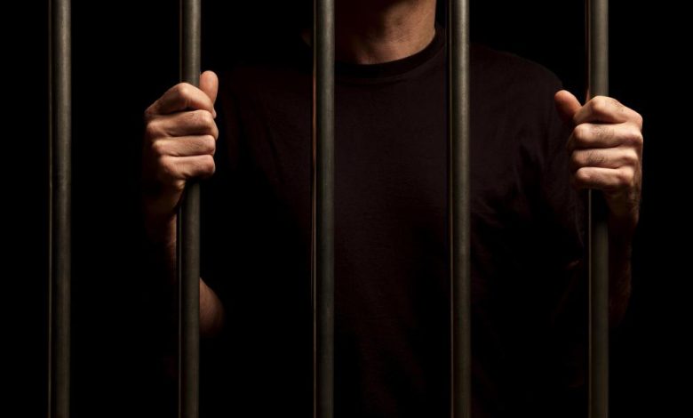 man in black shirt behind prison bars
